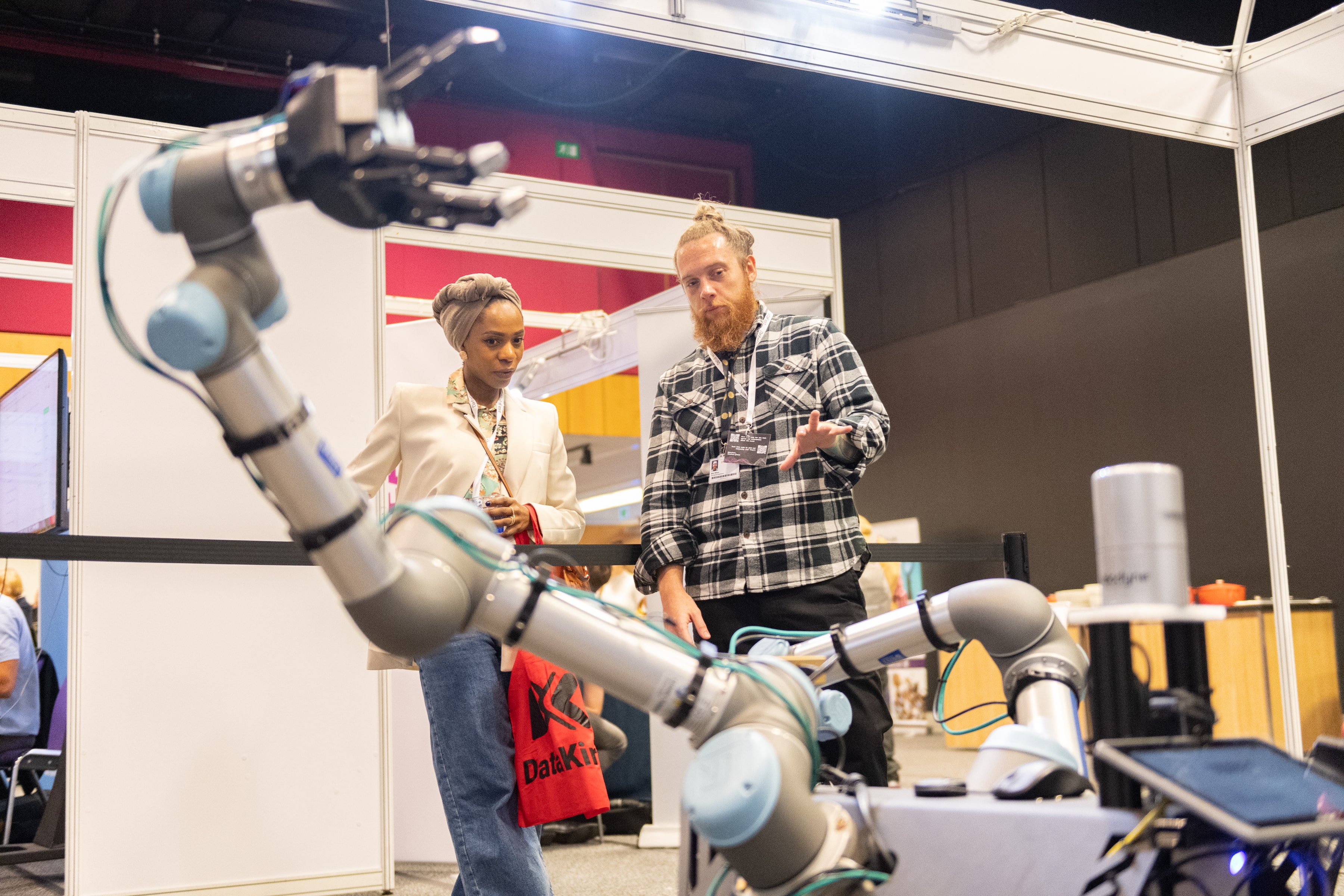 Two people looking at a robot in a conference space.