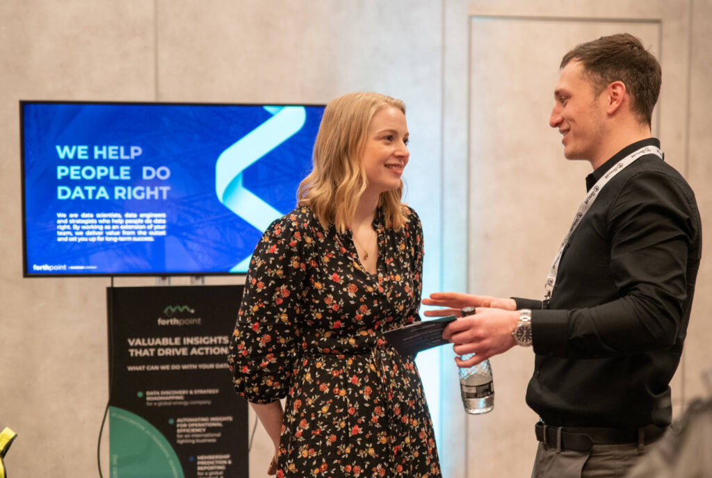 2 people talking infront of a screen that reads, we help people do data right