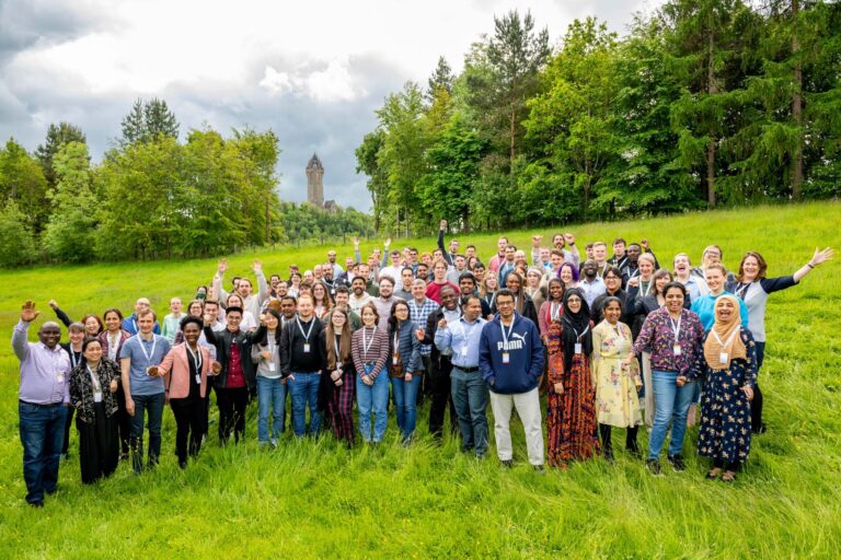 Photo of the MSc class of 2022 from The Data Lab Academy, standing in a field with their hands in the air