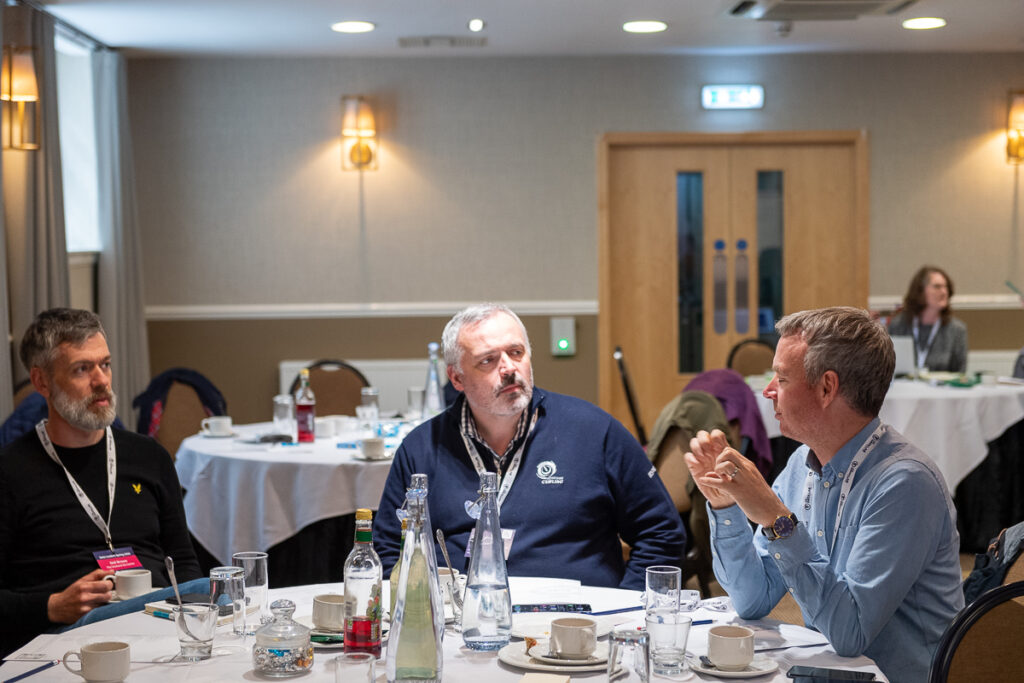 Three participants of the data leadership programme sit around a table in deep discussion