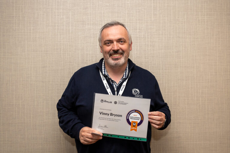 Vincent Bryson smiling brightly at the camera holding his certificate of completion for the Data Leadership Programme