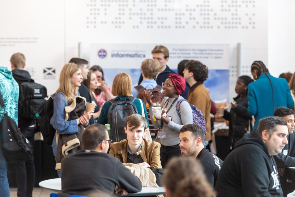 A large group of people standing, sitting and talking at a networking event.
