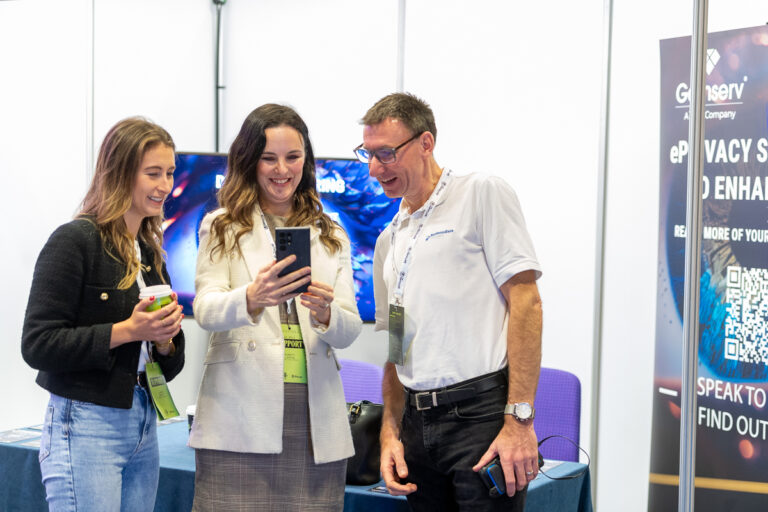 A group of three people looking at a phone, all smiling