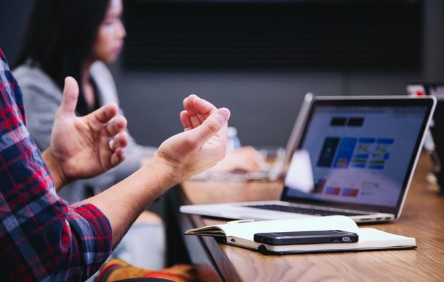 Two people having a discussion in front of a laptop