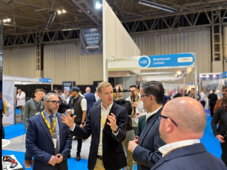 Photo of people attending an expo, three men in the foreground.