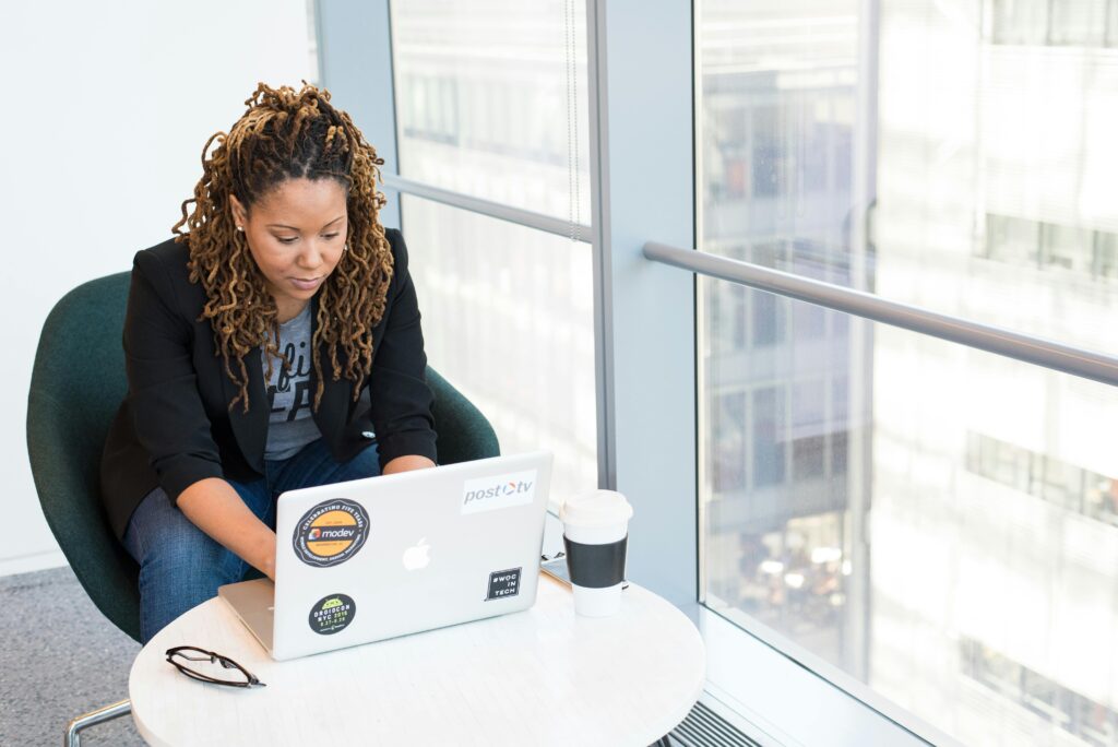 A woman sitting at a laptop with a coffee next to her.