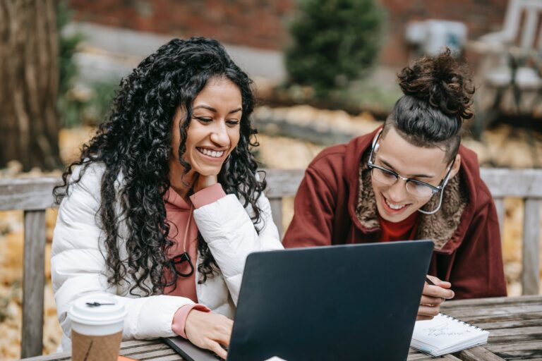 Two people smiling and looking at a laptop