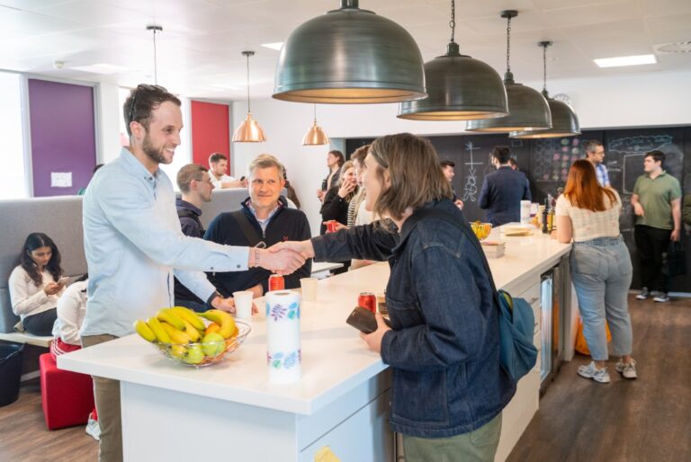 People shaking hands over a high table, at a networking event