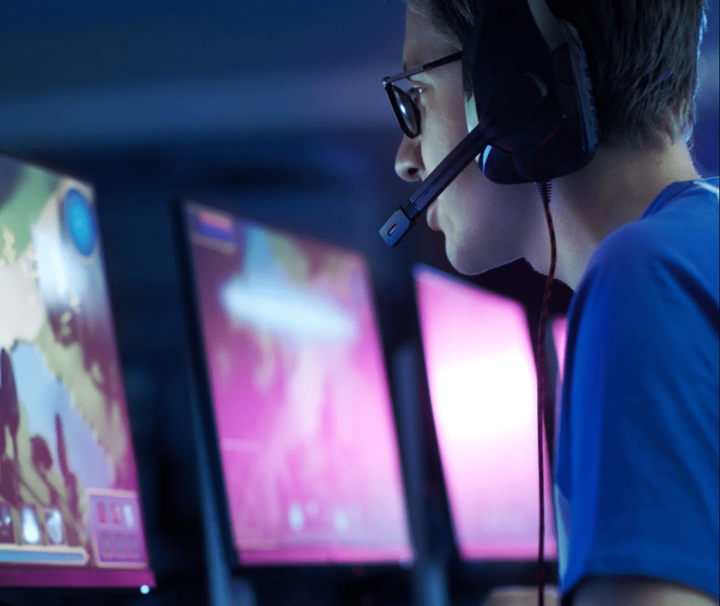 Photo of person wearing a gaming headset in front of computer screens